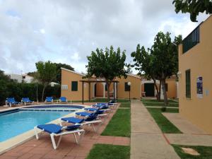 a row of lounge chairs next to a swimming pool at Apartamentos Surest in Cala en Blanes