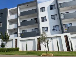 a large white apartment building with windows at Lovely Cozy Apartment in Midrand