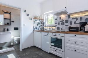 a kitchen with white cabinets and a sink and a toilet at Apartment Giardino, Ika-Opatija in Opric