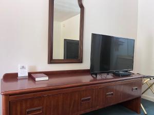 einen Fernseher auf einer Kommode mit Spiegel in der Unterkunft WINDTREE INN in Grove Hill