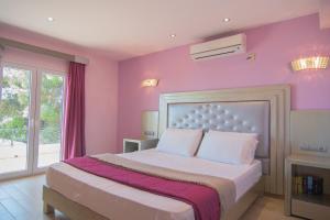 a bedroom with pink walls and a bed with white pillows at Villa Theodora View Apartments Klio in Corfu Town