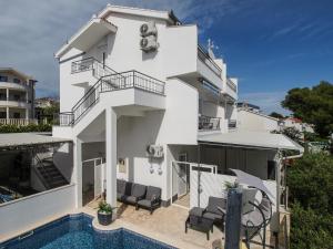 a white building with a swimming pool in front of it at Villa Sirenis in Trogir