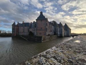 um grande castelo no meio de um corpo de água em Maison avec étang privé em Lignieres-Orgeres