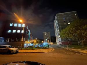 a city street at night with buildings and a car at Xtra large 1 bedroom London Flat in Woolwich