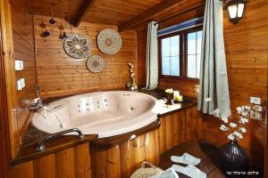 a bathroom with a tub in a wooden room at בקתה בתמרים in Moshav Ramot