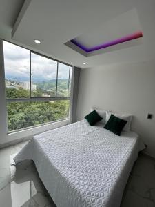 een slaapkamer met een wit bed en een groot raam bij Moderno apartamento con vista a las montañas in Manizales