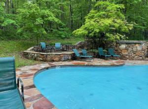a large swimming pool with chairs and a table at Hot Tub, Big Deck, Comm Pool, WiFi at Chalet Cabin in Berkeley Springs