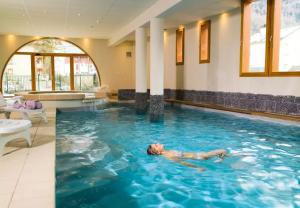 a man laying in the water in a swimming pool at Appartement Rés Cami Real, T2 cabine, 5 personnes, piscine intérieure in Saint-Lary-Soulan