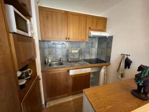 a small kitchen with wooden cabinets and a sink at Appartement Rés Cami Real, T2 cabine, 5 personnes, piscine intérieure in Saint-Lary-Soulan