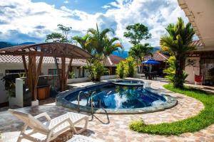 a pool in a backyard with chairs and an umbrella at La CASA DE LA ABUELA in Sucúa