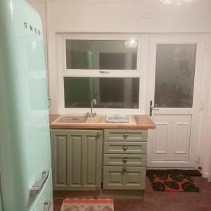 uma pequena cozinha com um lavatório e uma janela em Floss Cottage em Matson