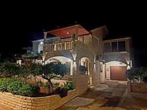 uma grande casa de tijolos à noite com uma cerca em APARTMENTS4YOU SUPETAR-the BEST and MOST POPULAR apartments for DISCOVERING the island em Supetar