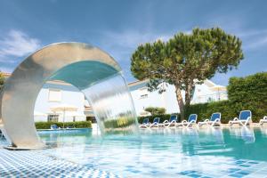 a fountain in a swimming pool with chairs at Hotel Neptuno in Atouguia da Baleia