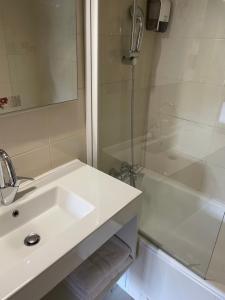 biała łazienka z umywalką i prysznicem w obiekcie Le Coq d'Or w mieście Brive-la-Gaillarde