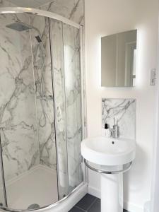 uma casa de banho branca com um chuveiro e um lavatório. em Inverness Highland Apartment em Inverness