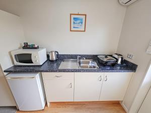 a kitchen with a sink and a microwave at Captain Cook Motor Lodge in Gisborne