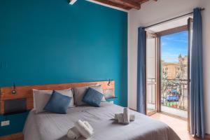 een blauwe slaapkamer met een bed en een groot raam bij Suk Ballarò House in Palermo