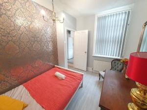 um quarto com um banco vermelho com um cobertor vermelho em Victorian Home, 3BR, Airport, M1, 6 beds, sleeps 12 em Luton