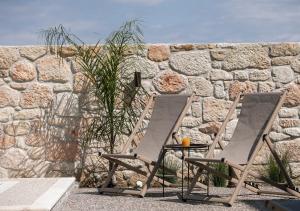 two folding chairs sitting next to a stone wall at VagAthan - Lux Holidays in Afitos