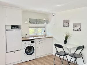 a white kitchen with a washing machine and a table at Cozy private annex near bathing lake and 30 min. from Copenhagen in Slangerup