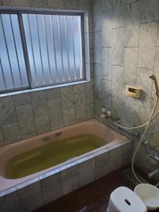 a bathroom with a tub with a toilet and a window at Guesthouse Tosa Hanare - Vacation STAY 14263 in Kochi