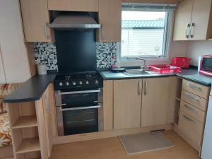 a kitchen with a stove and a sink at 6 berth pet friendly caravan on Sandy Glade (John Fowlers) Brean in Berrow