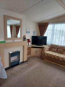 a living room with a fireplace and a television at 6 berth pet friendly caravan on Sandy Glade (John Fowlers) Brean in Berrow