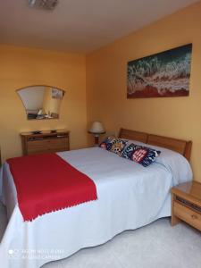 ein Schlafzimmer mit einem weißen Bett mit einer roten Decke in der Unterkunft ATICO AS CORTIÑAS in O Grove