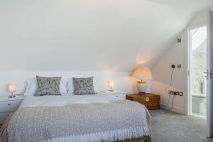 a bedroom with a bed and two lamps and a window at Beach Mews - Modern townhouse with patio and private parking in Kent