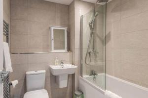 a bathroom with a toilet and a sink and a shower at Beach Mews - Modern townhouse with patio and private parking in Kent