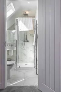 a white bathroom with a shower and a toilet at Beach Mews - Modern townhouse with patio and private parking in Kent