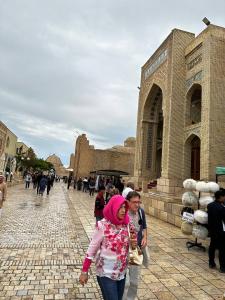 una mujer caminando delante de un edificio en SHAHRISTAN Plaza, en Bukhara