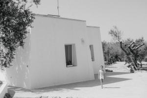Eine Frau, die vor einem weißen Gebäude steht. in der Unterkunft Sikalindi Apulian Farm&Living in Gagliano del Capo