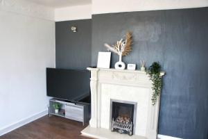a living room with a fireplace and a tv at Swinton, Manchester in Manchester