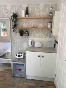 a small kitchen with white cabinets in a room at The Garden room in Honiton +18 photos