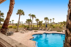a resort pool with palm trees and chairs at Portofino Island Resort & Spa 1-1402 in Pensacola Beach