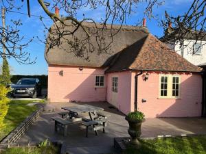 a pink house with a picnic table in front of it at Raspberry Cottage by Bloom Stays in Great Mongeham