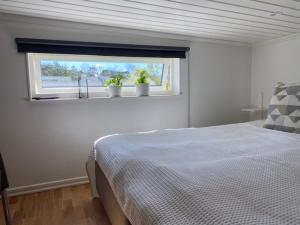 um quarto com uma cama e uma janela com vasos de plantas em Mycket trevlig stuga på Brännö med havsutsikt em Brännö