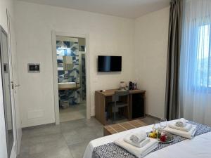 a room with a bed and a desk and a television at Calafato Guest House in Favignana