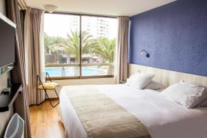 a bedroom with a large bed and a large window at Hotel Club La Serena in La Serena