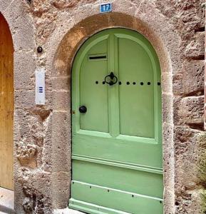 eine grüne Tür in einem Steingebäude mit einem Bogen in der Unterkunft Rooftop Agde in Agde
