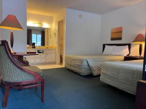a hotel room with two beds and a chair at WINDTREE INN in Grove Hill