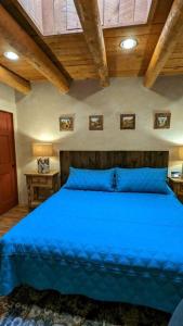 Una cama azul en un dormitorio con techos de madera. en Magical Santa Fe Stay, Minutes From Town Square, Sleeps 4, includes free parking and outdoor hot tub!, en Santa Fe