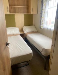 a small room with two beds and a window at Beach Caravan Holiday Home in Mablethorpe