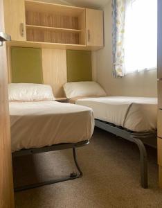 two bunk beds in a room with a window at Beach Caravan Holiday Home in Mablethorpe