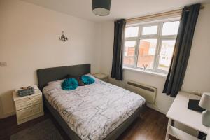 a bedroom with a bed with blue pillows on it at Luxury Central Luton - King-size Apartment - Free Parking - Free Wi-Fi - Near Shops & LTN Airport in Luton