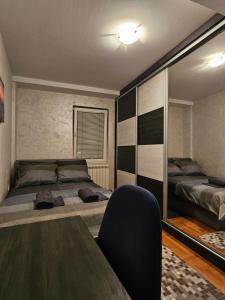a bedroom with two beds and a table with a chair at Duca apartmani in Šabac