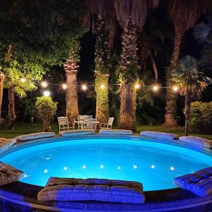 Orlando, quadrupla con bagno privato في ماسكالوتشا: مسبح كبير في الليل مع طاولة وكراسي