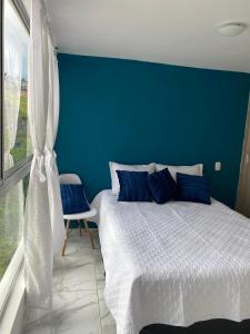 Dormitorio azul con cama y pared azul en Espectacular apartamento amplio y moderno a solo 20 min de termales, en Manizales
