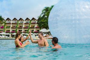 a group of people in the water with a giant ball at Grand Velas Riviera Maya - All Inclusive in Playa del Carmen